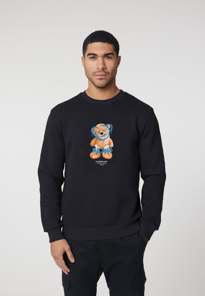 Black sweatshirt made of cotton featuring an orange bear graphic with blue accents and text "MILANO" on the front.