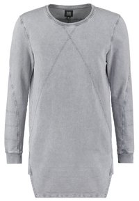 Pullover a maniche lunghe grigio chiaro realizzato in tessuto morbido. Presenta un collo rotondo, fasce laterali e dettagli con cuciture diagonali.