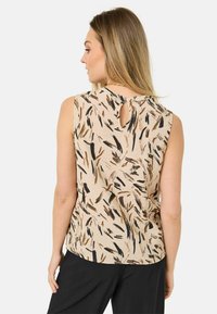 Bezrukávý béžový top s černými a hnědými abstraktními vzory, s detaily klíčové díry na zádech a měkkou texturou. Vhodný pro každodenní nošení.