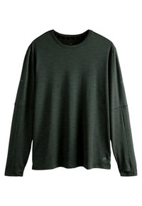 T-shirt vert foncé à manches longues, col rond, avec une texture subtile et une petite étiquette logo près de l'ourlet inférieur à droite.
