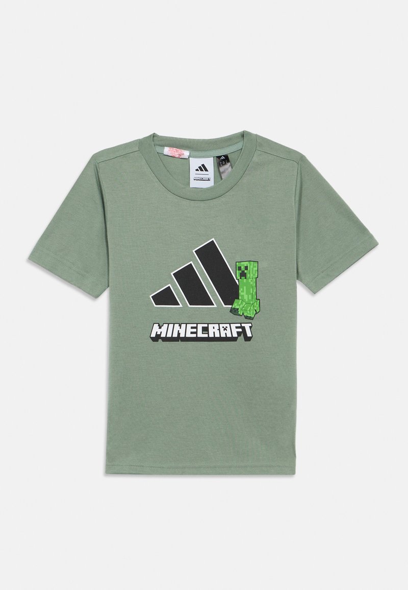 Zelena bombažna majica s kratkimi rokavi, ki ima črne Adidas stripe in grafiko Minecraft Creeper. Mehka tekstura, sproščen kroj.