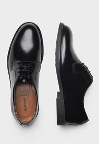 Scarpe eleganti in pelle nera con finitura lucida, design con lacci, texture liscia, punta rotonda e suola piatta in gomma.