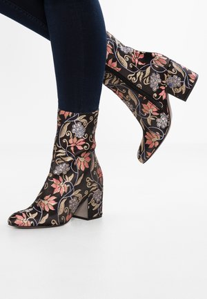 Bottines en tissu noir ornées de broderies florales colorées, avec un talon bloc haut et un ajustement serré, dotées d'une fermeture éclair sur le côté.