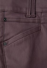 Tmavě mauve látka kalhot s přední kapsou a diagonálním švem, ozdobená dvěma černými knoflíky. Textura je hladká a viditelné švy.