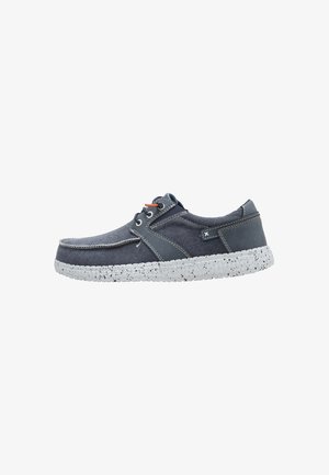 Chaussure décontractée bleu marine à lacets avec semelle blanche mouchetée, dessus en tissu et cuir, et détail de lacet orange contrastant sur le côté.