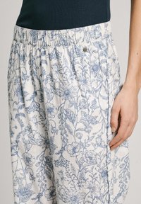 Pantalons légers avec un motif floral bleu sur fond blanc. Ils sont dotés d'une taille élastique et de poches latérales. Fabriqués en tissu respirant.