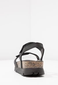 Sorte sandal med flere stropper, korklignende mellomsåle, solid svart yttersåle, glatt lærtekstur og justerbar lukking.
