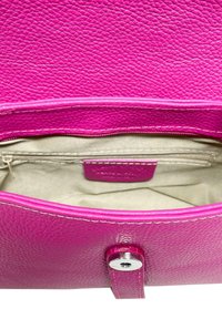Interno di una borsa in pelle rosa con finitura texturizzata, una tasca con zip e un rivestimento beige. Presenta una chiusura a scatto e dettagli di cucitura.