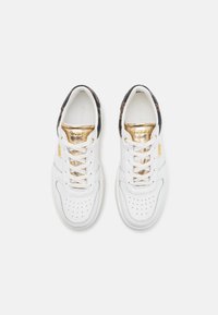 Sneaker bianche con accenti dorati e dettaglio a fantasia nera sul tallone. Presentano una punta perforata, occhielli dorati e linguetta con marchio.