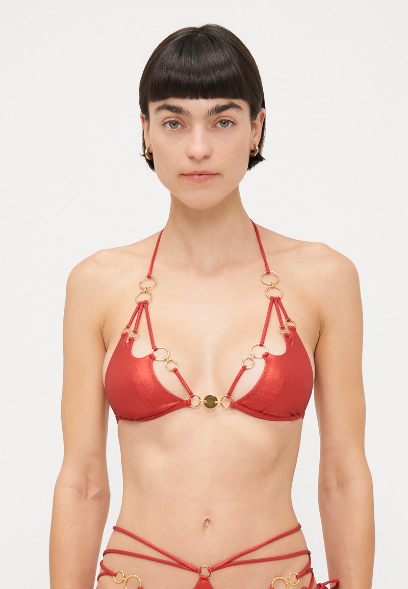 Red bikini top made of shiny material, featuring gold circular hardware accents, triangular cups, and thin adjustable straps.