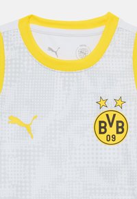 Hvit og gul fotballtrøye med Borussia Dortmund (BVB) logo og Puma-logo på brystet, gul kant på ermene og halsen.