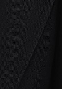 Fekete szövet sima tapintású és enyhe fényű, párhuzamosan átlós szövéssel. A kép éles éleket és redőket emel ki.