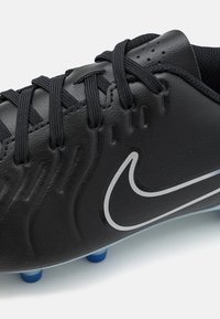 Čierne futbalové kopačky s hladkým koženým zvrškom, textúrovaným bočným dizajnom, čiernymi šnúrkami a strieborným logom Nike. Obsahujú modré kolíky na podrážke.
