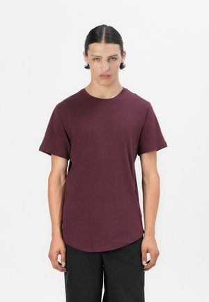Bordeauxfarbenes T-Shirt mit Rundhalsausschnitt aus weichem Material, mit kurzen Ärmeln und einem abgerundeten Saum für eine lockere Passform. Schlichtes Design, ohne Muster oder Akzente.