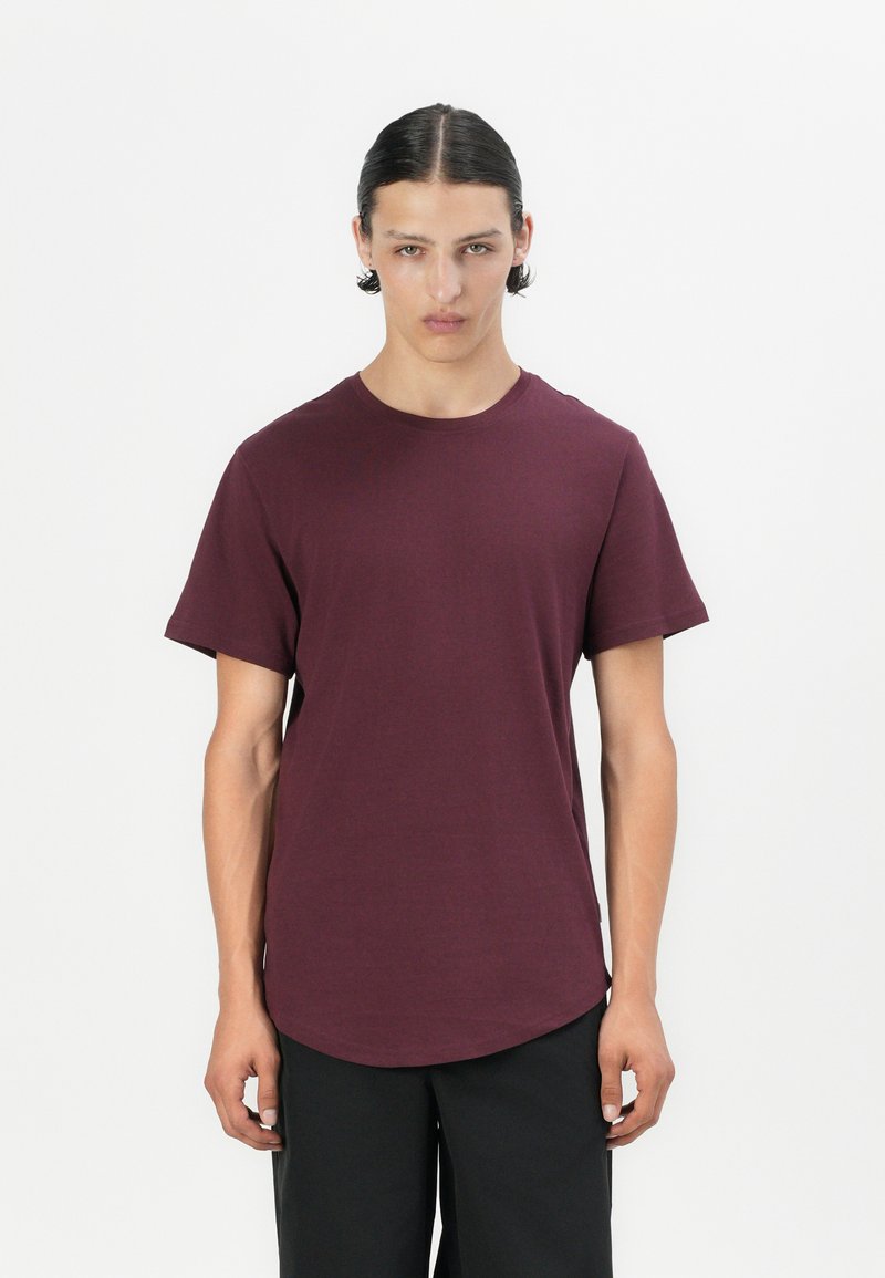 Camiseta de cuello redondo burdeos hecha de tejido suave, con mangas cortas y un dobladillo curvado para un ajuste relajado. Diseño sencillo, sin patrones ni acentos.
