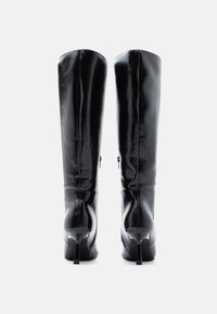 Μαύρες δερμάτινες μπότες μέχρι το γόνατο με γυαλιστερό φινίρισμα, στενή σχεδίαση και τακούνια στιλέτο. Περιλαμβάνουν πλευρικούς φερμουάρ για εύκολη εφαρμογή.