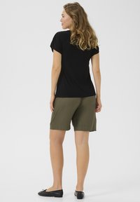 Haut noir à manches courtes associé à un short vert olive, tous deux en tissu doux. La tenue présente une coupe décontractée et un design simple.