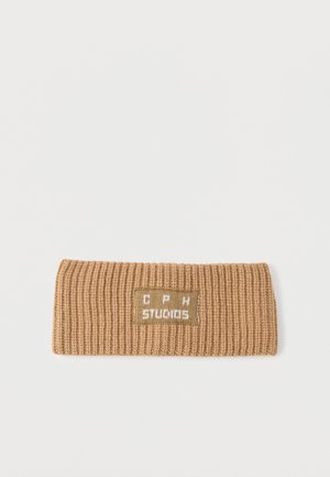 Knit headband in light brown, featuring a ribbed texture. Includes a stitched label with "CPH STUDIOS" in white on a green background.