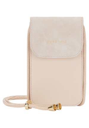 Kleine beige Umhängetasche mit Wildlederklappe, goldenem „EXPATRIÉ“-Logo und geflochtenem Riemen mit goldenen Metallenden.