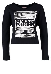 T-shirt court noir à manches longues avec texte blanc usé « IN SKATE WE TRUST » à l'intérieur d'un design rectangulaire rayé.