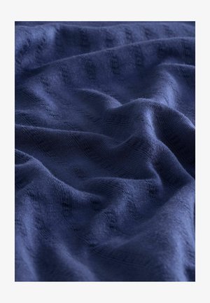Tissu texturé bleu marine avec des vagues douces, doté d'un motif ribbed subtil. Le matériau semble léger et tissé lâchement.