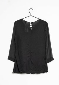 Blusa nera con maniche a tre quarti in parte trasparente, scollatura rotonda, apertura a chiave sul retro e orlo curvo. Tessuto morbido, texture liscia.