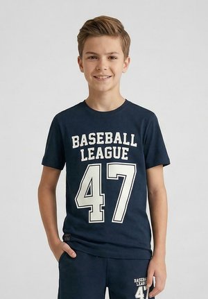 Tienerjongen glimlachend, draagt een donkerblauw t-shirt en korte broek met daarop in het wit "BASEBALL LEAGUE 47" gedrukt op beide.