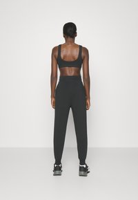 Svart sport-BH och matchande tapered joggers i elastisk tyg. Joggers har resårmidja och avslut i anklarna.
