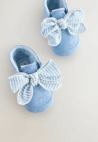 Pantofi din material albastru deschis cu un design matlasat și o fundă mare în dungi. Interior captusit cu un model în carouri alb și albastru deschis.