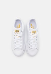 Vita lädersneakers med en mjuk yta, som har rund tå, platta snören och guld-logotyp på tungan och sidan.