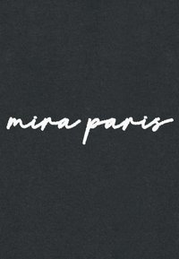 Tessuto nero con testo bianco in corsivo che recita "mira paris", con una superficie liscia e un leggero motivo a coste.