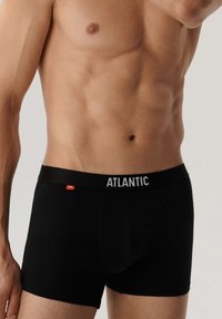 Czarne bokserki wykonane z gładkiego materiału z szerokim elastycznym pasem oznaczonym napisem "ATLANTIC" w białym kolorze, z małą czerwoną metką po boku.
