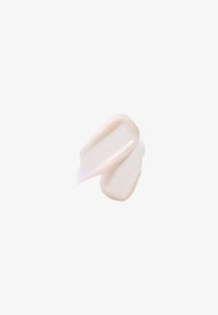 Deux traces de crème ou lotion beige clair sur un fond blanc, montrant une texture lisse et une finition brillante.