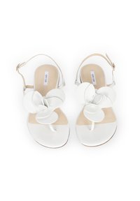 Białe sandały z kwiatowym wzorem, z dużymi nakładającymi się płatkami, paskiem między palcami oraz paskiem na kostkę z klamrą. Gładka tekstura.