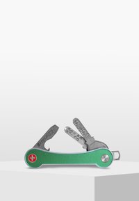 Green metal multi-tool key holder with a Swiss cross emblem, featuring silver tools, screwdriver, and a compact, ergonomic design.