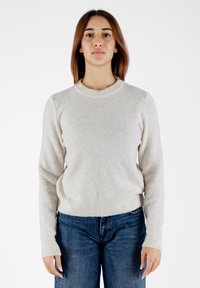 Maglione lavorato a maglia beige chiaro, con scollatura rotonda e maniche lunghe. Tessuto con texture, aderente in vita, indossato con jeans a vita alta.