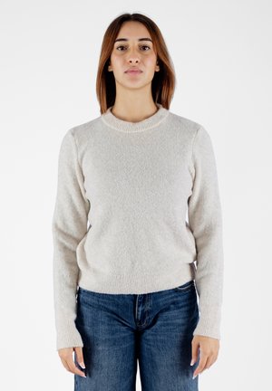 Maglione lavorato a maglia beige chiaro, con scollatura rotonda e maniche lunghe. Tessuto con texture, aderente in vita, indossato con jeans a vita alta.