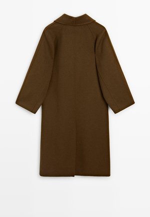 Cappotto lungo in lana marrone con colletto classico, maniche ampie e taglio dritto. Presenta uno spacco centrale sul retro per una maggiore libertà di movimento.