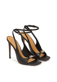 Zwarte leren hoge hakken sandalen met een vierkante neus, verstelbare enkelbandjes en een kleine metalen gespaccent aan de voorkant.
