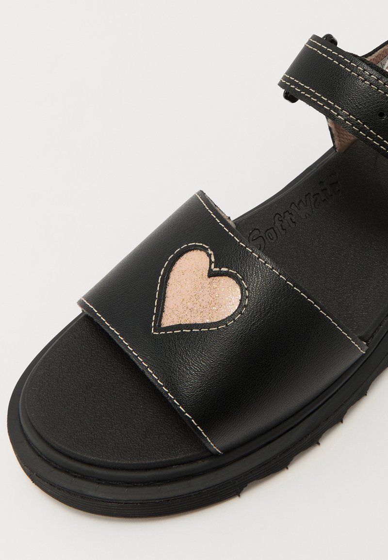 Sandale en cuir noir avec une large lanière ornée d'un design de cœur pailleté rose, des coutures contrastantes et une semelle texturée.