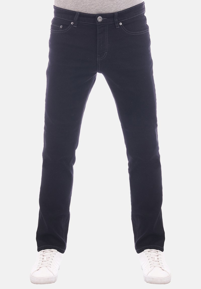 Jeans de mezclilla negra con corte recto, diseño de cinco bolsillos, costura en contraste y cierre de botones. Combinados con zapatillas blancas.