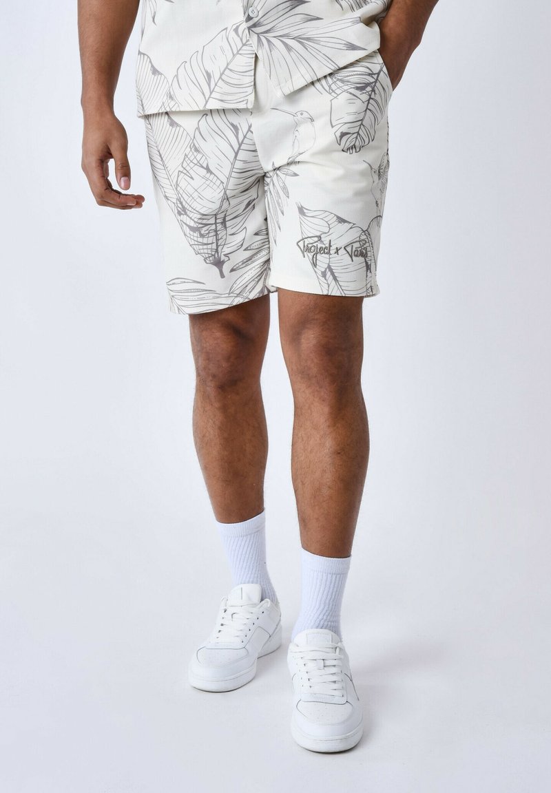 Pantalones cortos blancos con un patrón de hoja de palma en gris claro. Fabricados con un tejido texturizado, cuentan con bolsillos laterales y un detalle de logo en el dobladillo.