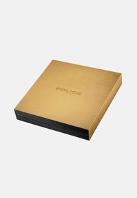 Scatola rettangolare dorata e nera con "POLICE" impresso sul coperchio dorato, posizionata su sfondo bianco semplice.