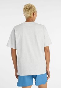 Grå kortärmad t-shirt med en avslappnad passform, tillverkad av ett mjukt material. Har en enkel design med en rak fåll och en blygsam rundad halsringning.