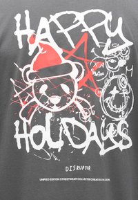 Siva majica kratkih rukava s grafičkim dizajnom medvjeda u crvenoj božićnoj kapici, crvenim prskanjem boje i velikim bijelim natpisom "SRETNI PRAZNICI."