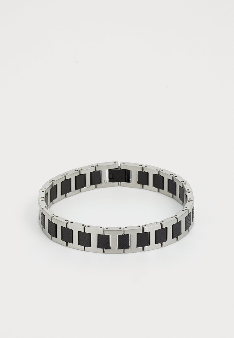 Strieborný kovový náramok s alternujúcimi čiernymi akcentmi, obdĺžnikovými článkami, hladkým povrchom a textúrovanými prvkami pre kontrast.