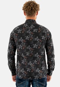 Camicia a maniche lunghe in tessuto nero con motivo floreale caratterizzato da fiori grigi e ruggine. Colletto standard e polsini con bottone. Vestibilità sartoriale.