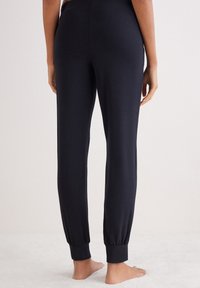 Svarta joggerbyxor i mjukt material, med en tapered bendesign och elastiska muddar. Lättviktigt material som passar för avslappnad användning.