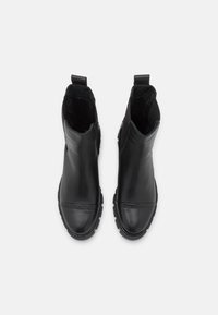 Svarta läderankelstövlar med rundad tå, elastiska sidopaneler och en strukturerad sula. Har subtila sömmar och en dragflik.