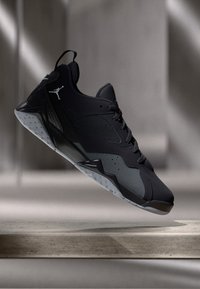 Μαύρο αθλητικό παπούτσι με υφή στην επάνω πλευρά, απαλό μεσαίο πέλμα και καουτσούκ στην εξωτερική σόλα. Διαθέτει λογότυπο και διακριτές γραμμές σχεδίασης.